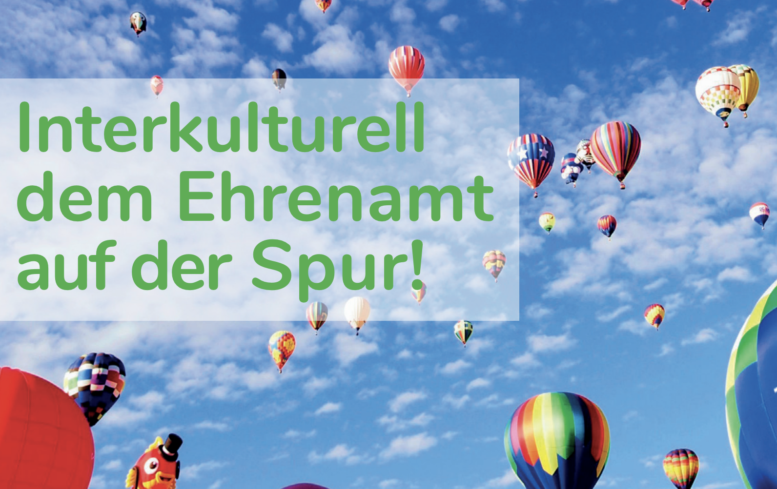 Ein Himmel mit vielen bunten Luftballons und der Aufschrifft "Interkulturell dem Ehrenamt auf der Spur!"