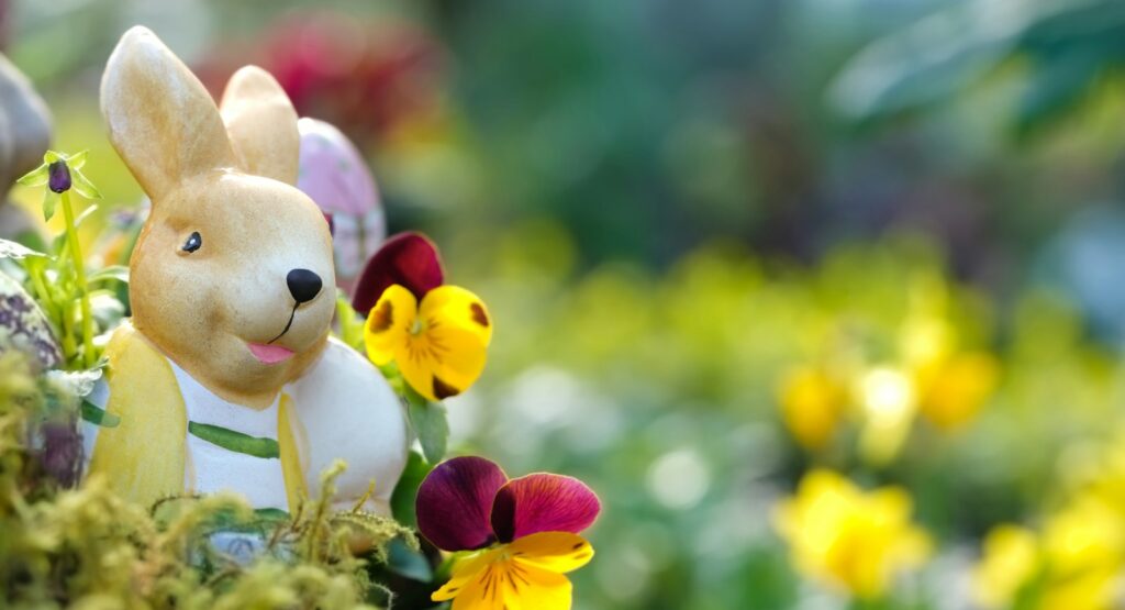 a close up of a toy rabbit in a field of flowers