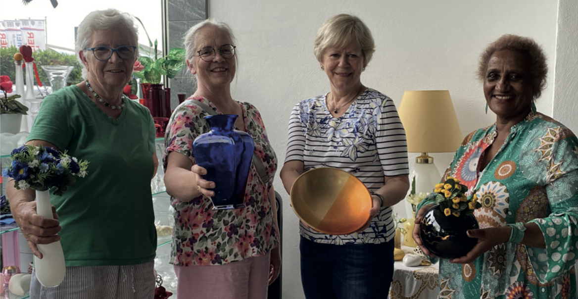 4 Frauen die nebeneinander stehen und Produkte aus dem Second Hand Kaufhaus hochladen.