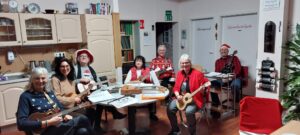 mehrere Menschen sitzen um einen Tisch an Gitarren