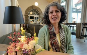 Frau mit gelockten schwarz-grauen-Haaren und einem buntem Schal