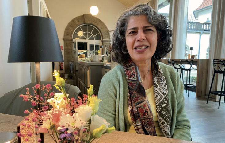 Frau mit gelockten schwarz-grauen-Haaren und einem buntem Schal